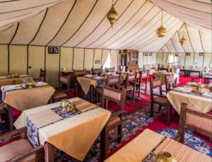 a restaurant with tables and chairs in a tent at Merzouga Beduien Camping in Merzouga