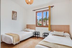 two beds in a room with a window at Paradise Dúplex Garden & Beach Maspalomas in San Bartolomé
