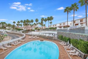 a swimming pool with lounge chairs and palm trees at Paradise Dúplex Garden & Beach Maspalomas in San Bartolomé