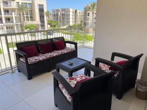 a balcony with two chairs and a couch and a table at Chalet in marassi marina pool view exm80 in El Alamein
