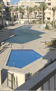 a large blue swimming pool with palm trees and buildings at Chalet in marassi marina pool view exm80 in El Alamein +5 photos