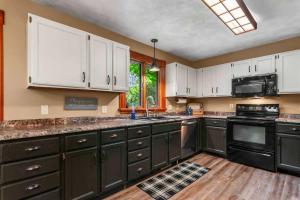 a kitchen with black appliances and white cabinets at Lakeside Getaway includes Hot Tub pet friendly in Gaylord
