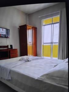 a bedroom with a large bed and a window at Hotel e Flat Sobral Mundi in Sobral
