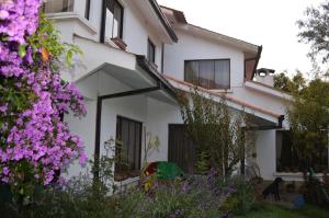 a white house with purple flowers in front of it at Casa en Obrajes in La Paz