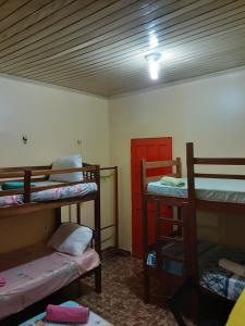 a room with three bunk beds and a red door at Albergue Flor do Caribe in Parintins