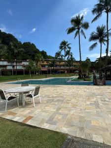 un patio con tavolo e sedie accanto alla piscina di Angra Green Coast Residence Service e Marina ad Angra dos Reis Altre 77 foto
