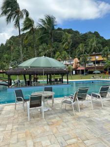 un tavolo con sedie e un ombrellone accanto alla piscina di Angra Green Coast Residence Service e Marina ad Angra dos Reis