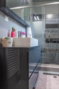 a bathroom with a sink and a glass shower at Chill Vibes Luxurious Living House in Volos