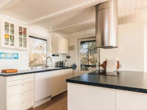 a kitchen with white cabinets and black counter tops at Secluded Beach Retreat - By Traum Ferienwohnungen in Lihme +16 photos
