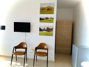 a room with two chairs and a tv on a wall at Vila Rahmi & Veli Dervishaj in Vlorë