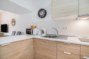 a kitchen with a sink and a clock on the wall at Paradise Dúplex Garden & Beach Maspalomas in San Bartolomé +20 photos