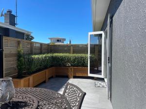un patio con tavolo, sedie e una recinzione di Gold Star Haven a Napier