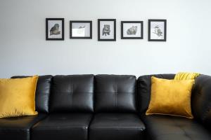 a black leather couch with yellow pillows against a wall at Villa 4 NEW 3Bed 2 Bath in Warrane