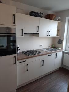 a kitchen with white cabinets and a stove and a sink at Charmantes, helles City-Apartment - nahe Hafen, Schloss & Altstadt in Schwerin