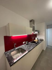 a kitchen with a sink and a red wall at My Home in Dornbirn