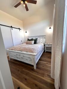 a bedroom with a white bed with a ceiling fan at Posh Cottage Wine Country Mountain View Retreat in Palisade