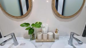 a bathroom sink with two mirrors and a vase with a plant at Cây Trôm Homestay 1 in Vĩnh Hy