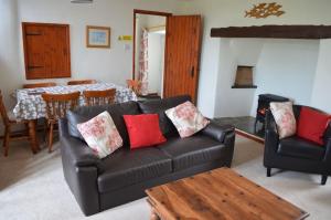 ein Wohnzimmer mit einer Ledercouch und einem Tisch in der Unterkunft Bowood Cottage in Abbotsham