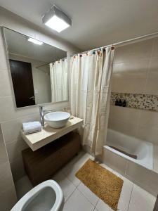 a bathroom with a sink and a toilet and a tub at Departamento Condominio del Alto 3 H&L in Rosario