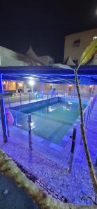 a swimming pool at night with blue lights at فلة و شاليه واسع بمسبح وثلاث غرف نوم ومجلس شعبي ومجلس مناسبات in Riyadh