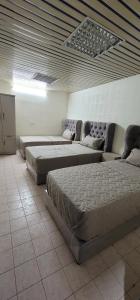 a room with three beds and a couch at فلة و شاليه واسع بمسبح وثلاث غرف نوم ومجلس شعبي ومجلس مناسبات in Riyadh