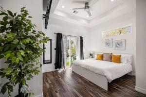 a white bedroom with a bed and a potted plant at Modern and Serene Oasis Mins from Downtown Houston in Houston