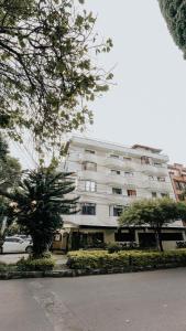 メデジンにあるHotel Balcones del Estadioの前に木々がある大きな白い建物