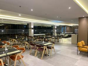 a restaurant with tables and chairs and a bar at LYNN Hotel Tuban in Tuban