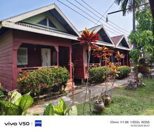 a red house with plants in front of it at DONDET Garden Guest House in Don Det