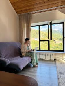 Eine Frau, die auf einer Couch mit einem Laptop sitzt. in der Unterkunft Жайсан in Karakol