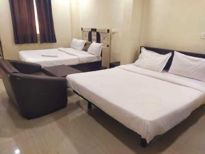 a room with two beds and a chair in it at Hotel O Galaxy Hospitality in Pune