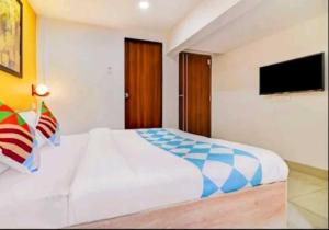 a bedroom with a white bed and a flat screen tv at Hotel O Galaxy Hospitality in Pune