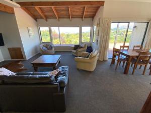 een woonkamer met een bank, stoelen en een tafel bij Ridgehouse Wanaka in Wanaka +8 foto's