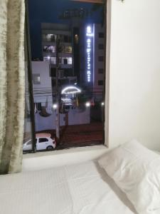 - une fenêtre de chambre avec un lit blanc et une vue sur la ville dans l'établissement Imbanaco Centro Medico Apartamento Estadio, à Cali 5 autres photos