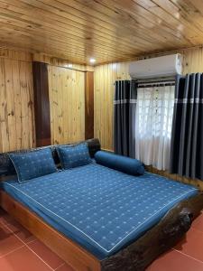 un grand lit dans une chambre aux murs en bois dans l'établissement Pơ Lang Farmstay, à Bien Ho