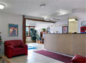 a lobby with a red chair and a counter at Microtel Inn & Suites by Wyndham Gallup - PET FRIENDLY in Gallup