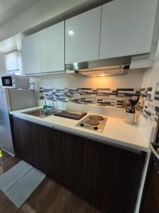 a kitchen with white cabinets and a sink at Air Residences Makati - fully furnished condo with skyline views! in Manila