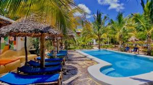 a resort pool with blue chairs and palm trees at Kameleon Blue Arts Lodge in Kizimkazi