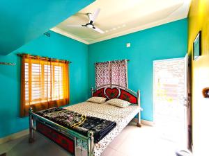 a bedroom with a bed in a blue room at Abhinandan Homestay in Shānti Niketan