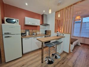 a kitchen with a white refrigerator and a wooden table at Studio calme centre-ville Châteauroux avec parking - FR-1-591-725 in Châteauroux