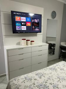 阿瓜斯迪林多亚Aconchegante Flat Cavalinho Branco Águas de Lindóia的卧室配有梳妆台,墙上配有电视