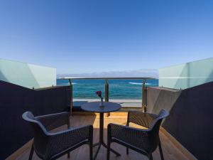 a balcony with two chairs and a table with a view of the ocean at Sercotel Playa Canteras in Las Palmas de Gran Canaria
