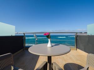 a table with a vase of flowers on a balcony with the ocean at Sercotel Playa Canteras in Las Palmas de Gran Canaria