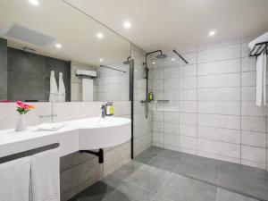 a bathroom with a white sink and a shower at Sercotel Playa Canteras in Las Palmas de Gran Canaria