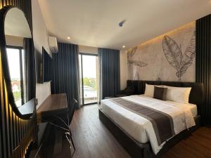a bedroom with a bed and a desk and a mirror at LION 16 Hotel in Can Tho