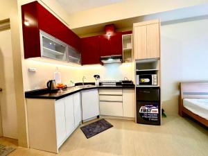 a small kitchen with red cabinets and a bed at Avida Towers Aspira Tower 1 in Cagayan de Oro