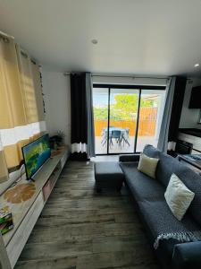 a living room with a couch and a view of a patio at Villa Ranitea - maison moderne avec piscine privée in Avae +26 photos