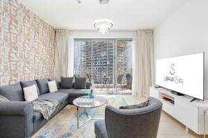 a living room with a couch and a tv at Ultimate Stay 2 BR Next to Burj Khalifa with Opera & Fountain Views in Dubai