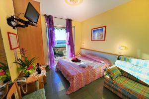 a bedroom with a bed and a couch and a tv at Hotel Lucerna in Arma di Taggia