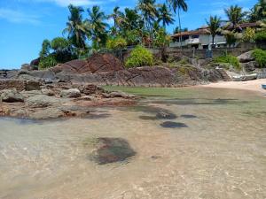 a beach with rocks and a house in the background at Chapel Home Stay in Ahungalla